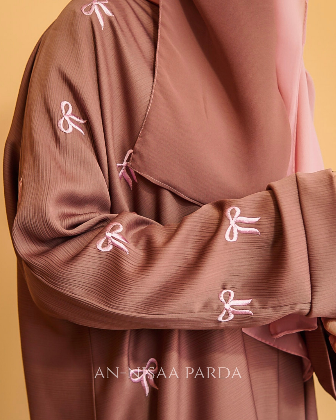 Close-up of small embroidered bows on gown fabric, showing texture and detail